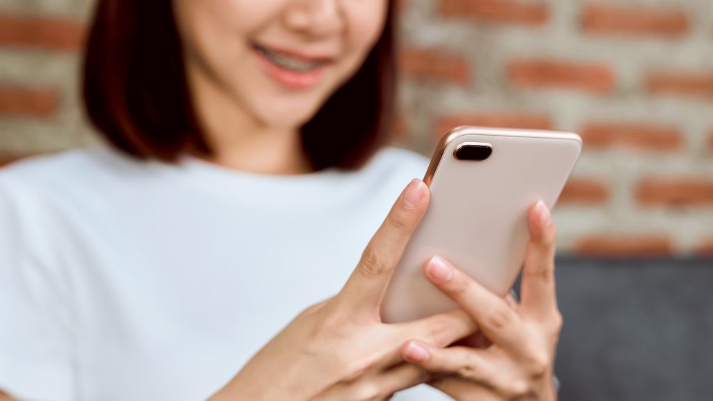 笑顔でスマートフォンを操作する女性