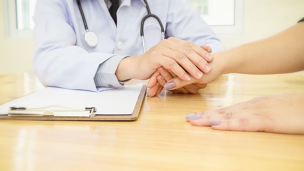 患者の手を握る医師