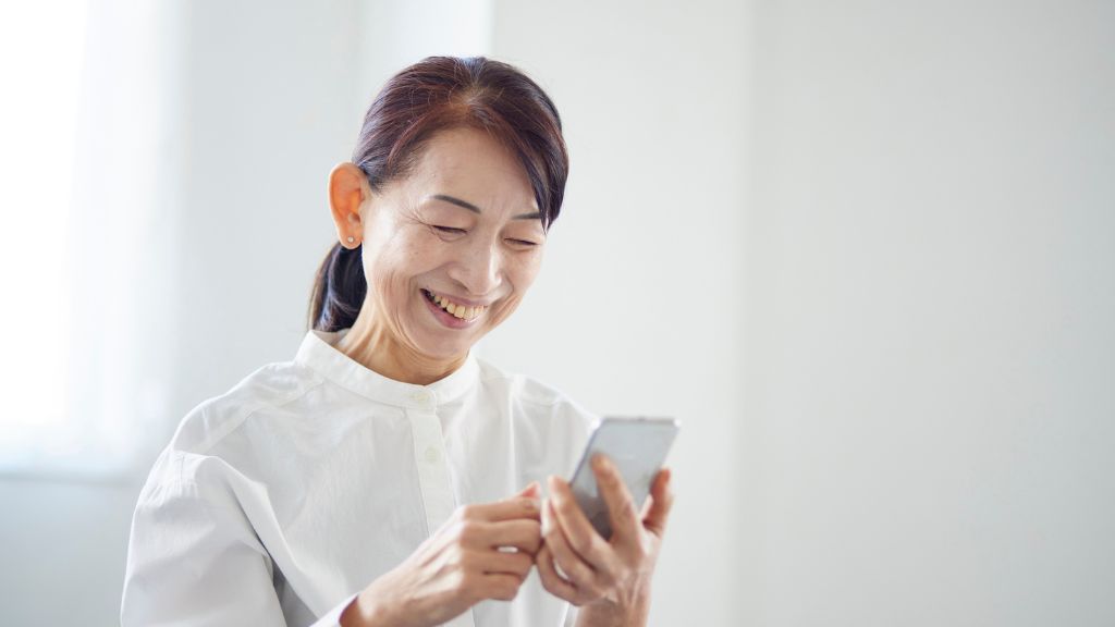 スマホを笑顔で操作する高齢者